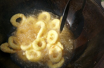 Calamari rings in deep frying in pan. Close up of frying onion rings in the fryer in hot oil.