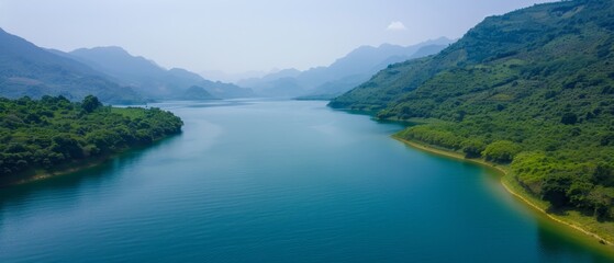  A large body of water surrounded by lush green hills and a forest-covered mountain range lies beyond it