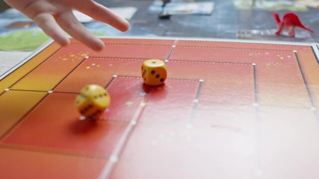 The hand throws yellow dices on the playing field. Gaming moments in dynamics. Luck and excitement. Board games strategy. Slow motion.