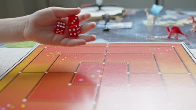 The hand throws red dices on the playing field. Gaming moments in dynamics. Luck and excitement. Board games strategy. Slow motion.