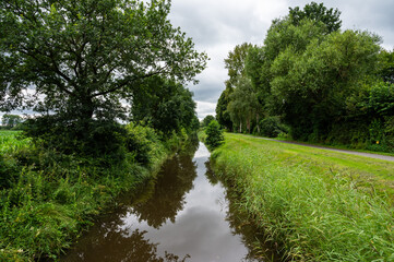 Tree reflections in a creek with cloudy sky around Fischerhude, Lower Saxony, Germany