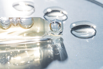 Pipettes with cosmetic gel product in petri dish on blue background. Skin care lab.