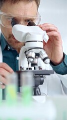 Man scientist with protective glasses using microscope in laboratory. Microbiology science concept