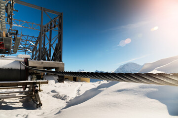 cable car towers, in the blue sky against the backdrop of snow-capped mountains. cable car...