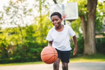 portrait of a boy kid playing with a basketball in park