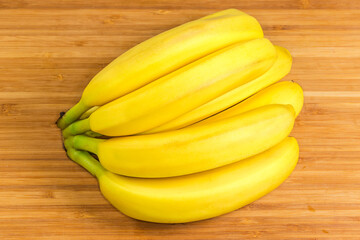 Cluster of ripe bananas on a wooden surface close-up