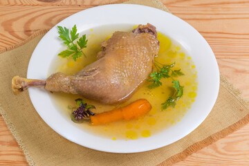 Boiled domestic chicken leg quarter in a bouillon on dish