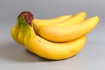Cluster of ripe bananas on a gray background close-up