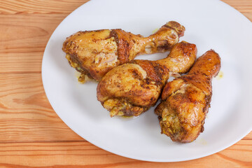 Baked chicken drumsticks on white dish on a rustic table