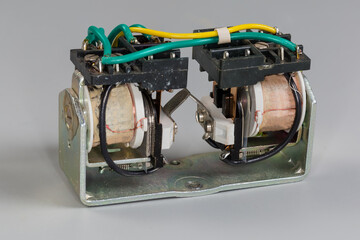 Electromechanical latching relay with two coils on gray background