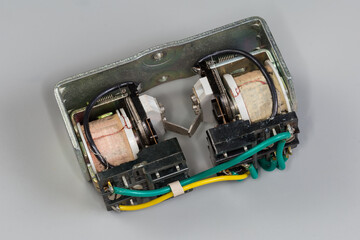 Electromechanical latching relay with two coils on gray background