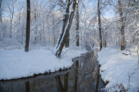 Onset of winter in the English Garden in Munich, Bavaria, Germany: Beautiful idyllic snowy landscape at the famous Eisbach stream on a sunny December day