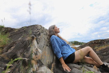 Woman sitting on stone coast. Woman relaxing by the fjord in Norway, Oslo.