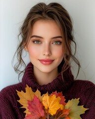 A woman in a purple sweater holding a bunch of autumn leaves