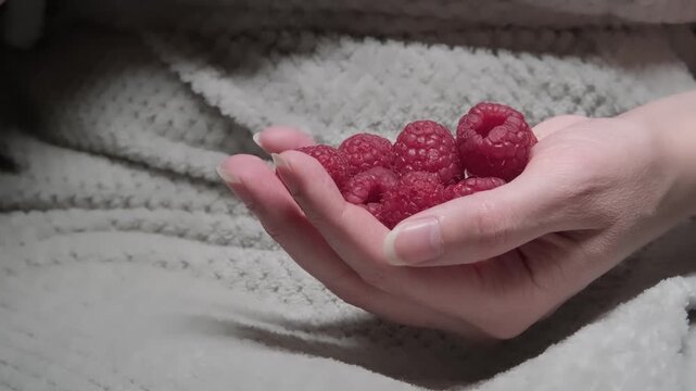 A woman eats delicious ripe raspberries. Close-up of