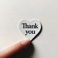 Finger holding heart-shaped "thank you" sticker on light background with copy space