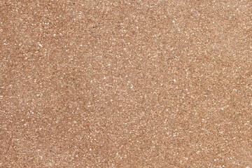 Close-up texture of brown rough wall surface with small stones and speckles, natural backgrounds