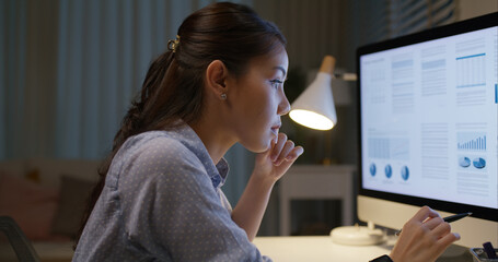 Young asia woman talent workforce people happy work hard late night busy sit at home office desk read sale plan report data online on desktop PC in hybrid workspace reskill upskill class for worker.