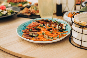 A festive and beautifully decorated wedding table. Decorated with flowers.various bottles of drinks, beautiful dishes, salads and sliced meat rolls.vegetable slicing.