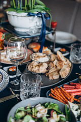 A festive and beautifully decorated wedding table. Decorated with flowers.various bottles of drinks, beautiful dishes, salads and sliced meat rolls.vegetable slicing.