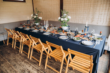 A festive and beautifully decorated wedding table. Decorated with flowers.various bottles of drinks, beautiful dishes, salads and sliced meat rolls.vegetable slicing.