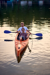 the couple in love kayaking on the river at sunset