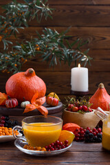 yellow tea with sea buckthorn berries in a glass teapot. Decorated with physalis and autumn pumpkins, sea buckthorn tea