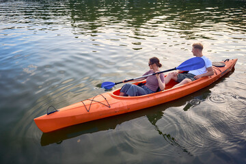 the couple in love kayaking on the river at sunset
