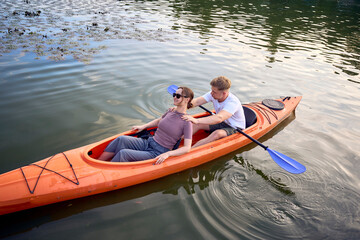 the couple in love kayaking on the river at sunset