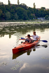 the couple in love kayaking on the river at sunset