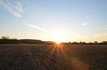 Sunrise on sunset in summer, sun rays over horizon with beautiful sky and landscape background