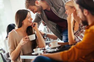Diverse young friends drinking coffee in busy cafe