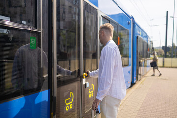 A young businessman in a stylish suit with a suitcase enters a tram. High quality photo
