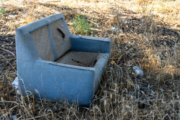 Plastic bottles and an old sofa discarded in a field, showcasing the disturbing impact of human...