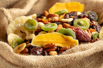 Dried tropical fruits and nuts in burlap bag.