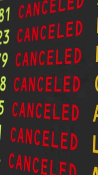 A close-up vertical view of an airport's travel information board with flights being cancelled, possibly due to bad weather conditions.	