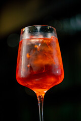 close-up of a wine glass on a black background with coarsely crushed ice in a glass orange Aperol...