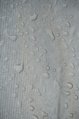 Extreme close up photograph of water droplets on a textured fabric. Vertical.