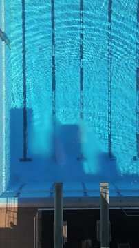 Aerial view of an empty swimming pool with diving platforms, showcasing clear blue water and serene surroundings. Perfect for sports, architecture, and recreation-themed projects