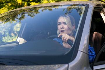 Stressed woman drive car feeling sad and shocked. Caucasian blond girl tired and feeling frustrated.