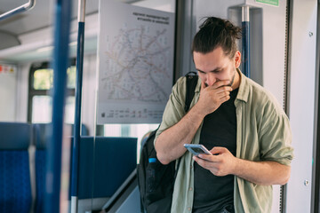 Fototapeta premium A frustrated Caucasian man on the train, in the skytrain, in the subway. Sad, stressed guy rides a train carriage in the afternoon.
