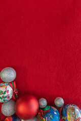 A Christmas flat lay featuring ornaments at the bottom of a red fabric background, with empty space for text. Ideal for holiday designs, greeting cards, or festive promotions