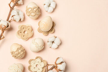 Craft eggs, knitted and cotton flowers on soft beige background. Top view. Copy space