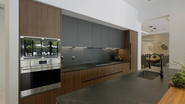 Modern kitchen interior with luxury cabinets and table top with view of garden through window. Contemporary design and architecture blending indoor and outdoor spaces