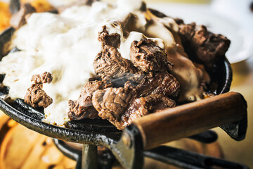 meat served with melted cheese on the plate. Hot food to be served in winter.
