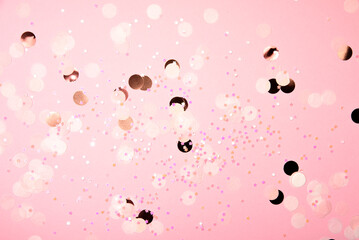Abstract background of scattered pink and gold confetti with bokeh lights, creating a festive and celebratory atmosphere.