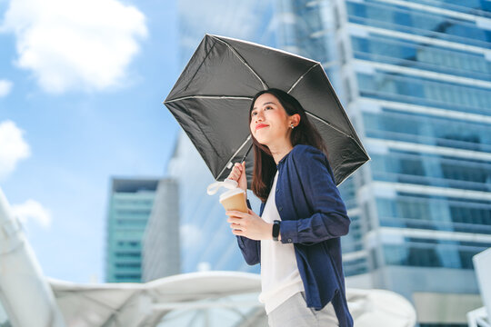 Business asian woman holding UV protection umbrella on sunny day city building background