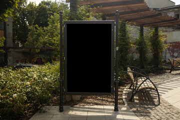 Mockup of the blank black street city outdoor advertising square billboard in black frame at park entrance. High quality photo