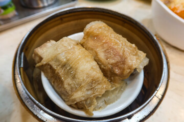 close up of Chinese Cantonese Dim Sum Steamed Chicken bean curd skin Roll with shrimp fish skin in a bamboo steamer container ordered in 