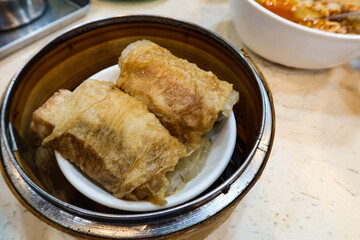 close up of Chinese Cantonese Dim Sum Steamed Chicken bean curd skin Roll with shrimp fish skin in a bamboo steamer container ordered in 